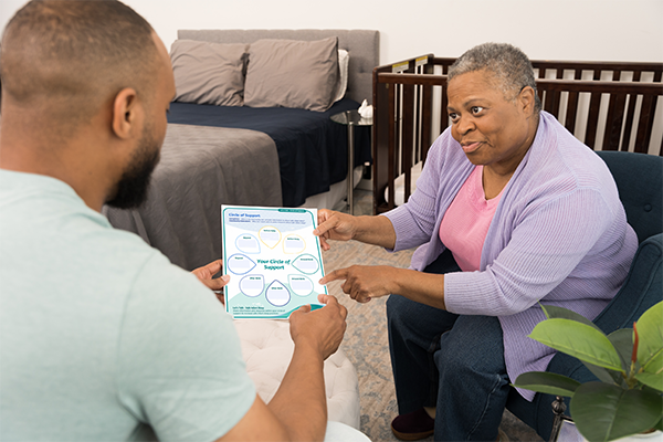 A Grandmother showing her son a Safe Infant Sleep Document.